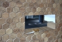 Na keramických obkladech v dekoru dřeva vyniká designové tlačítko ovládání toalety.